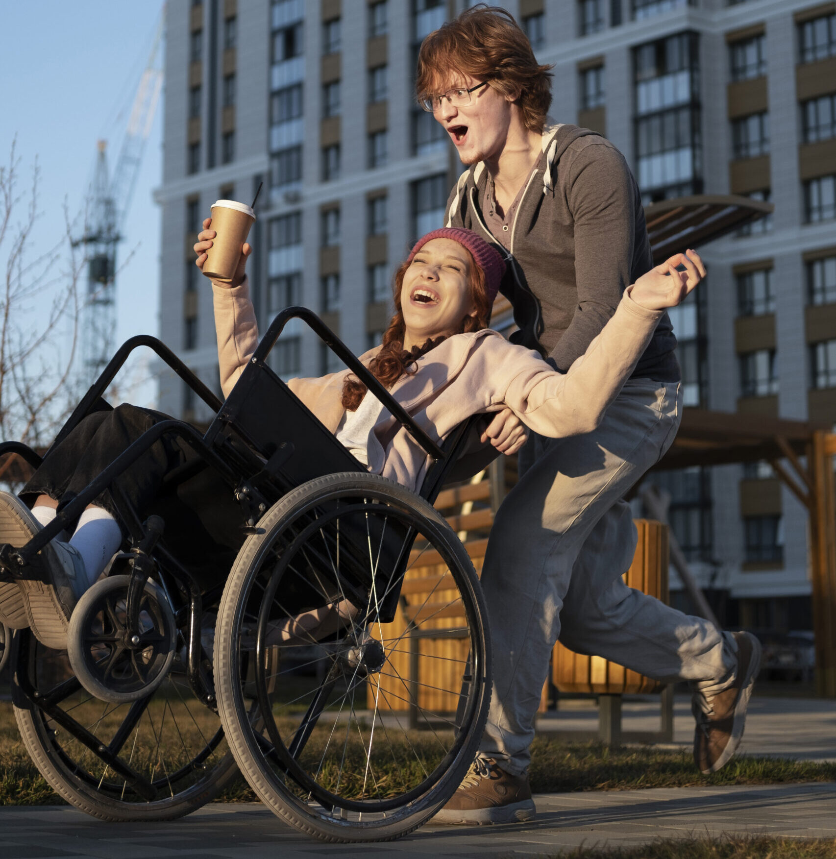 Two people in a wheelchair and one is holding a cup