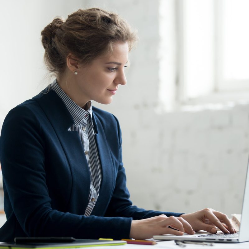 A woman in a suit and tie using her laptop.