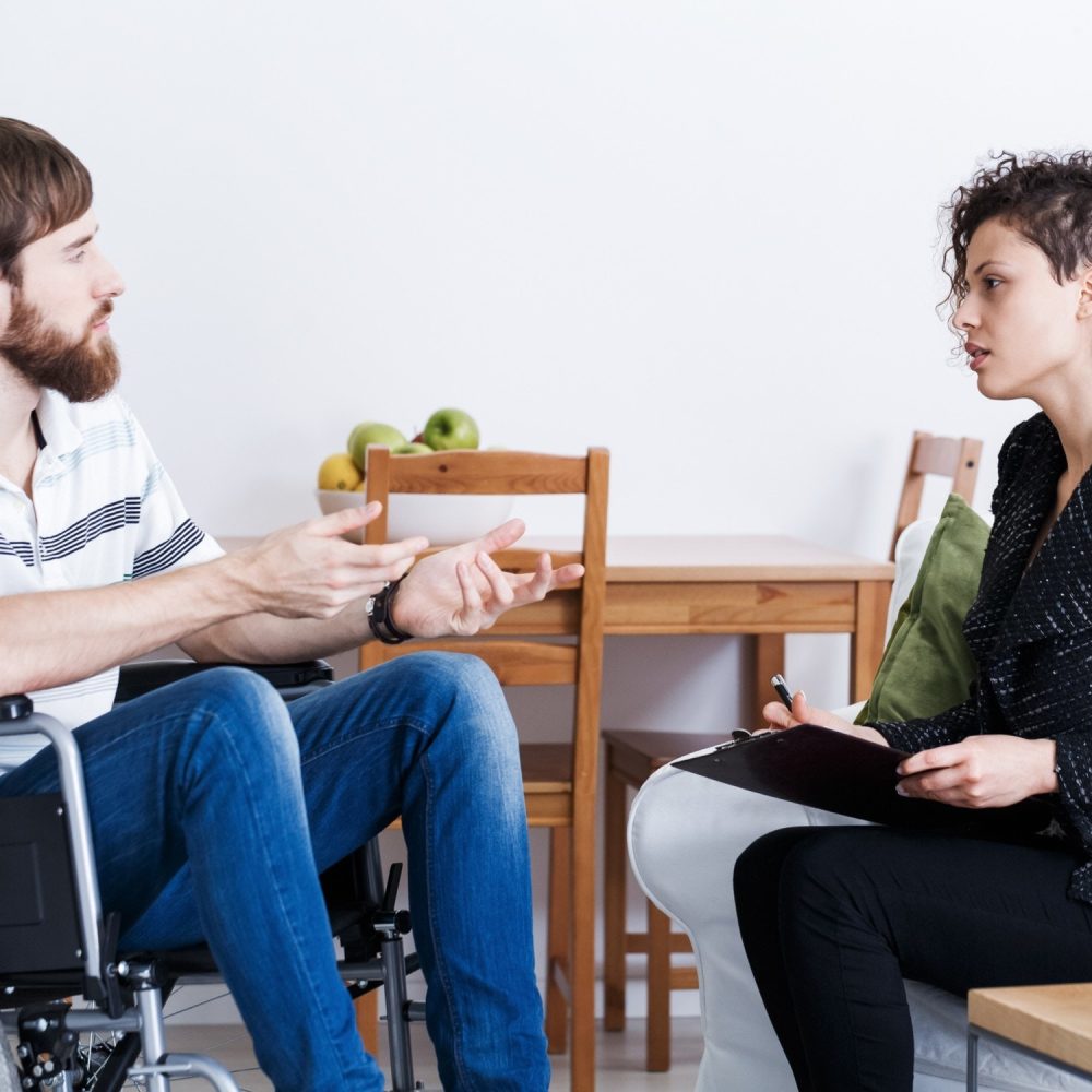 A man and woman are sitting in chairs talking.