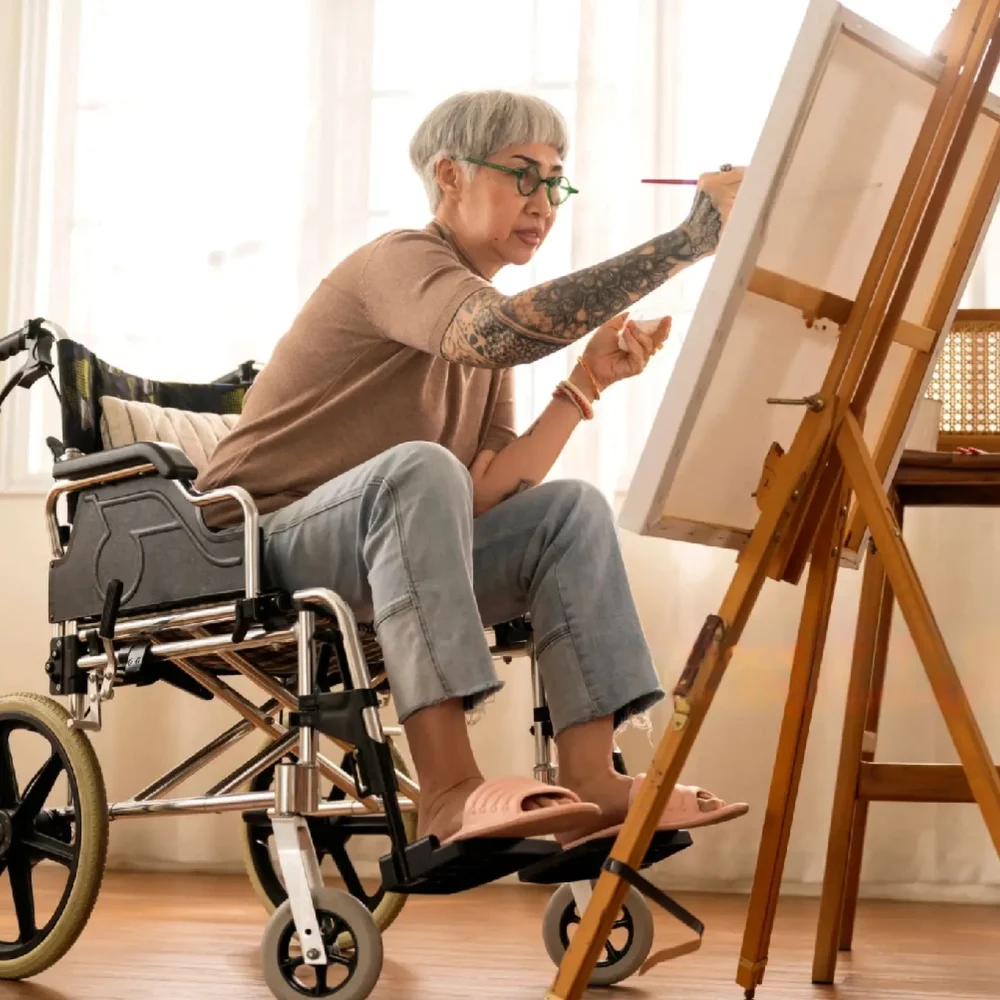 A person in a wheelchair painting on an easel.