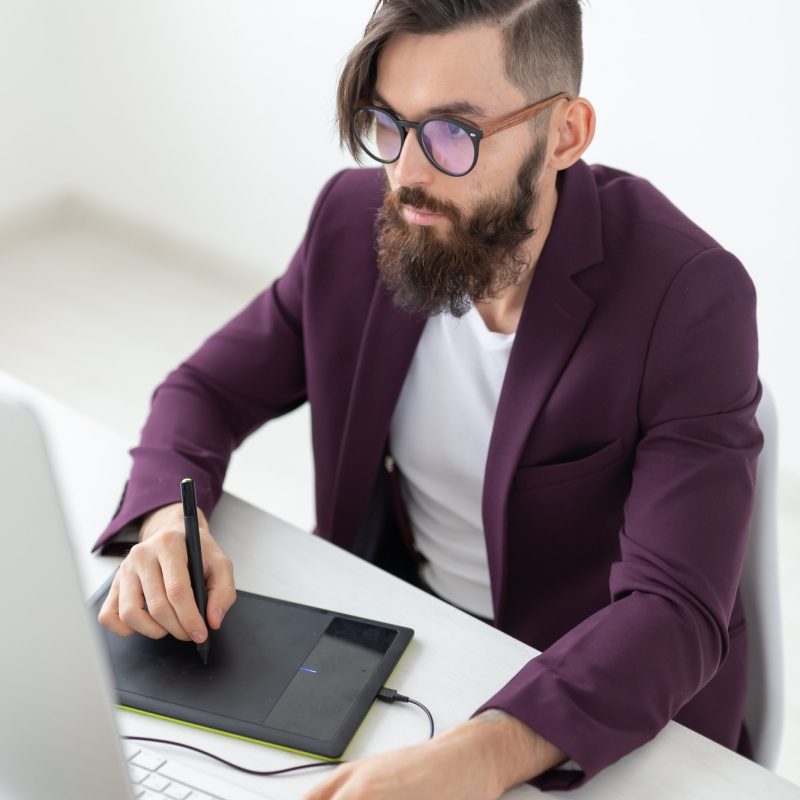 A man with a beard and glasses is using a tablet