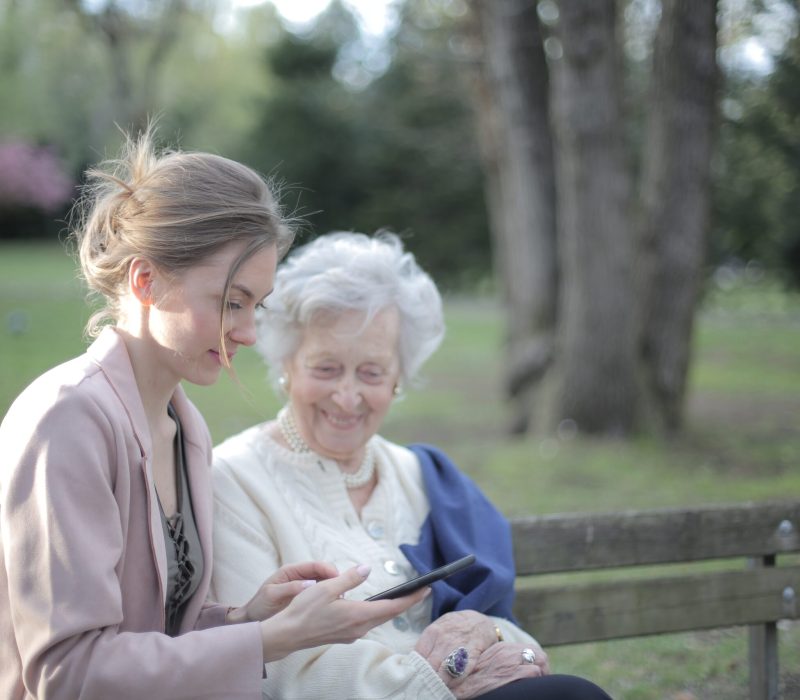 A woman and an older person looking at something on a phone.