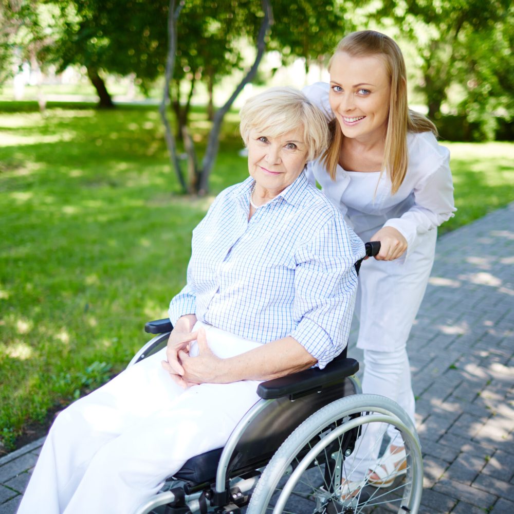 A woman pushing an older lady in a wheelchair.